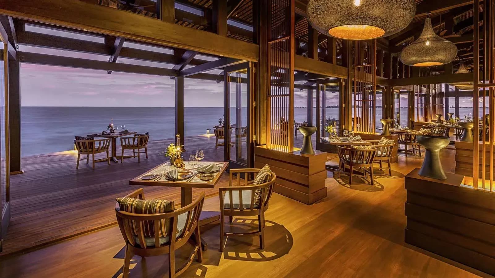 Keyolhu Restaurant dining room at sunset, overlooking the ocean at Kudadoo Maldives Private Island