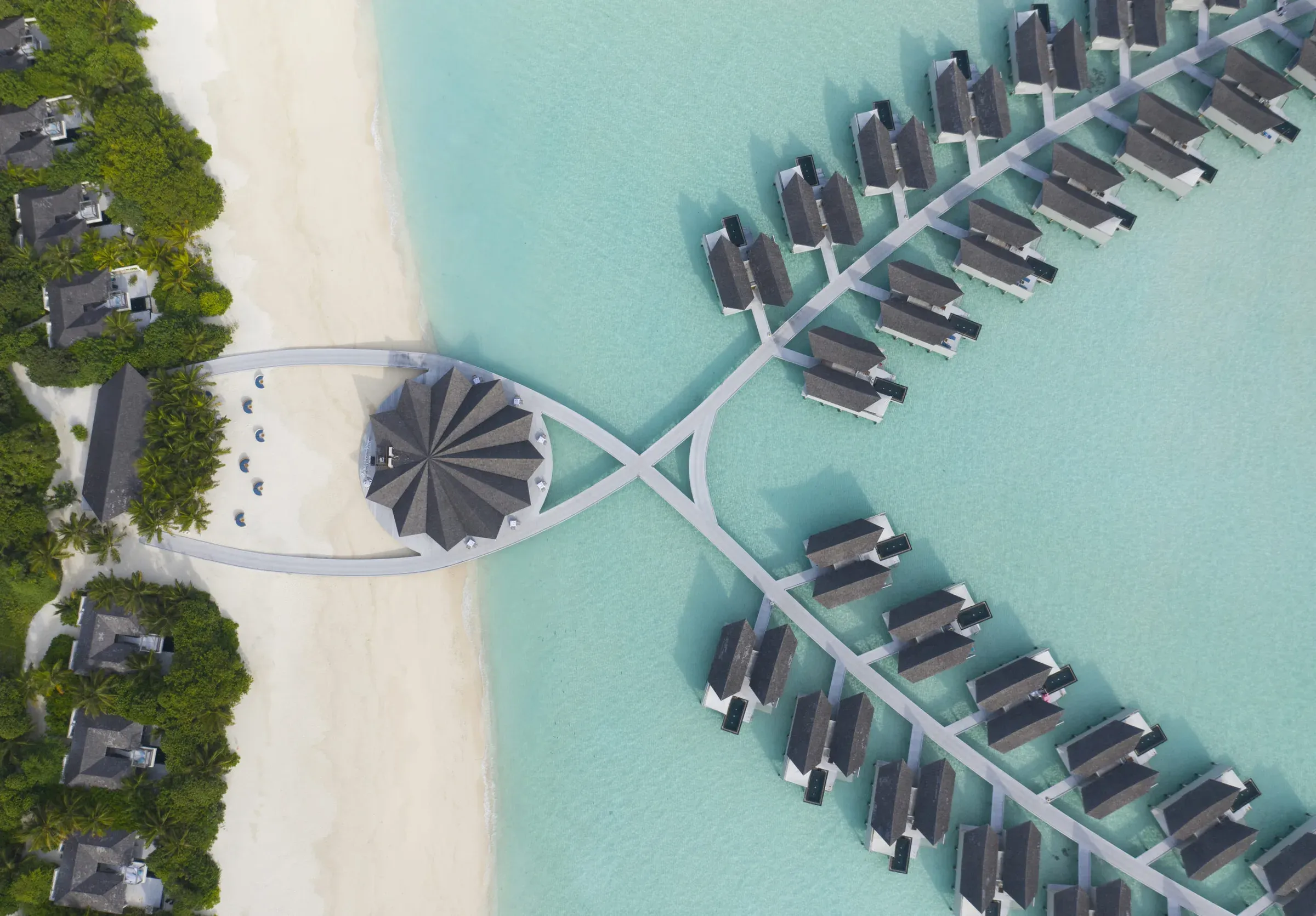 Aerial view of the overwater pool villas at Kuredhivaru Resort and Spa reaching out across the reef