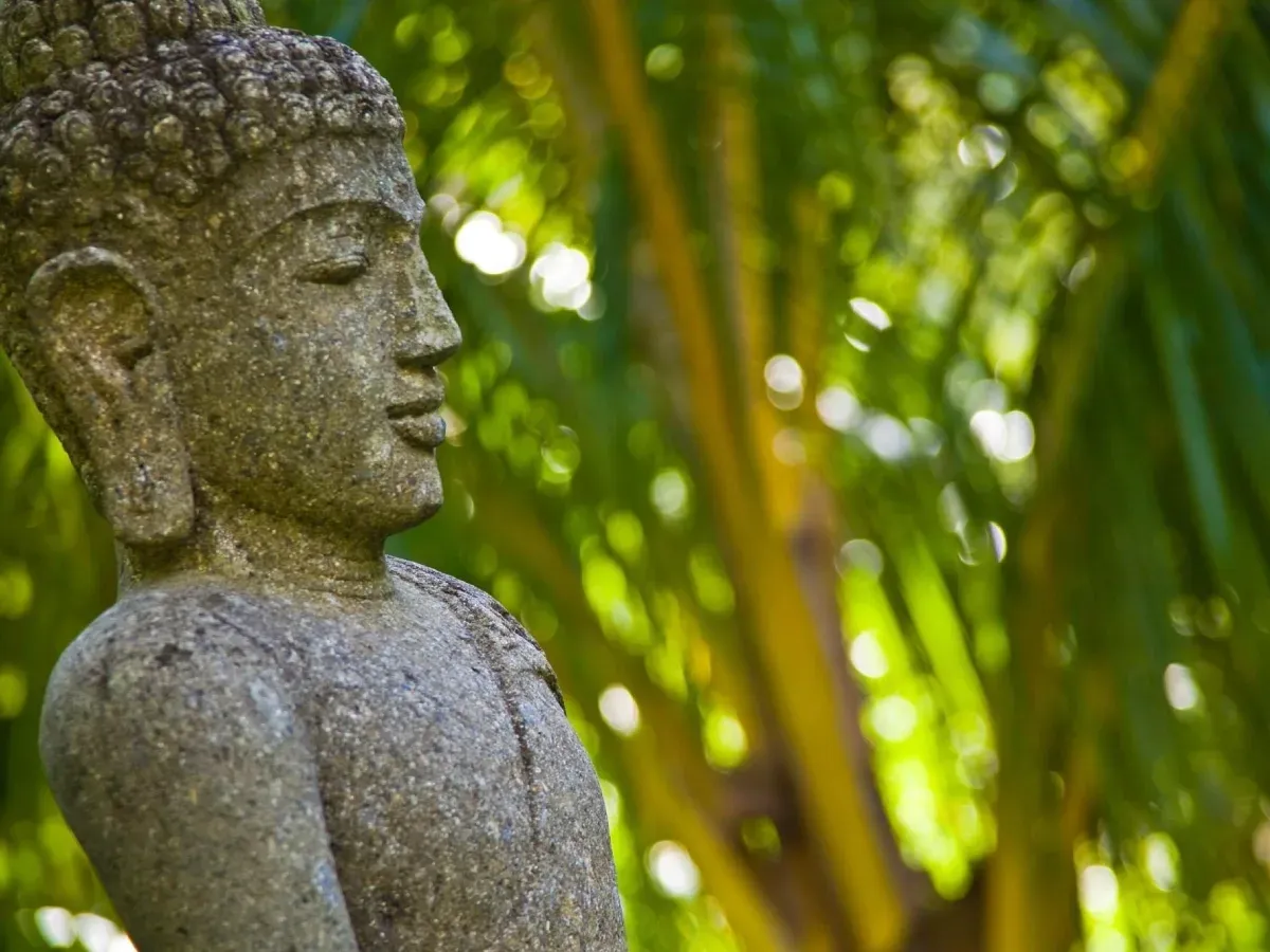 Stone Buddha statue among the greenery of the meditation garden at Lakaz Chamarel