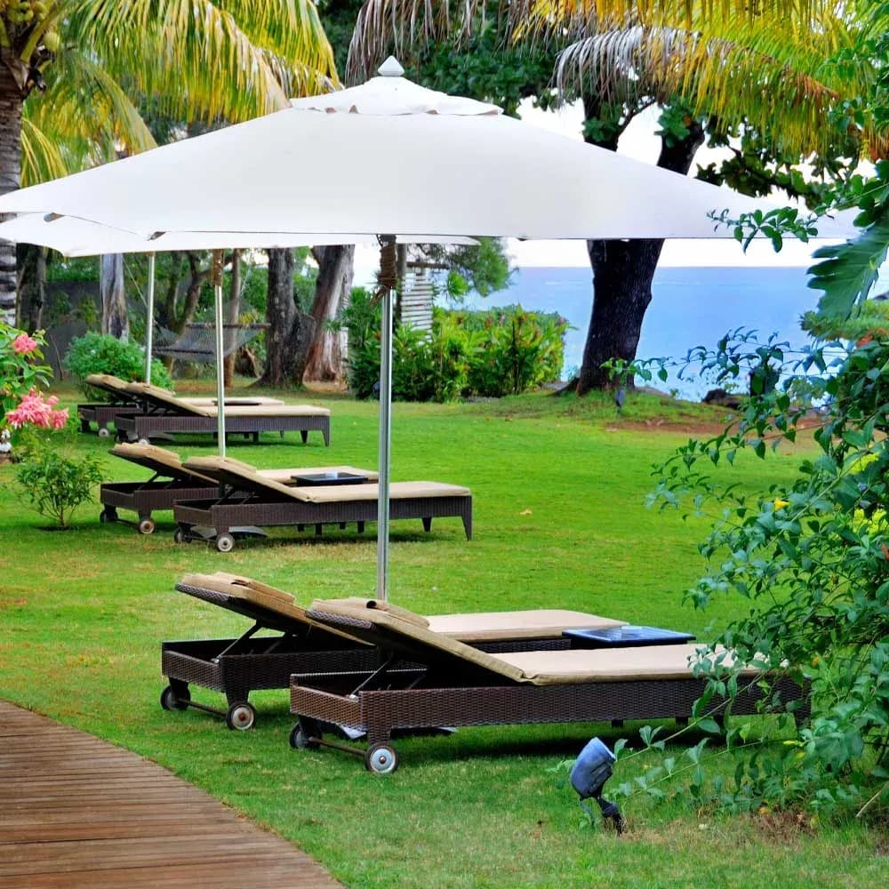 Sun loungers beneath palm trees overlooking the lagoon at Le Cardinal Exclusive Resort