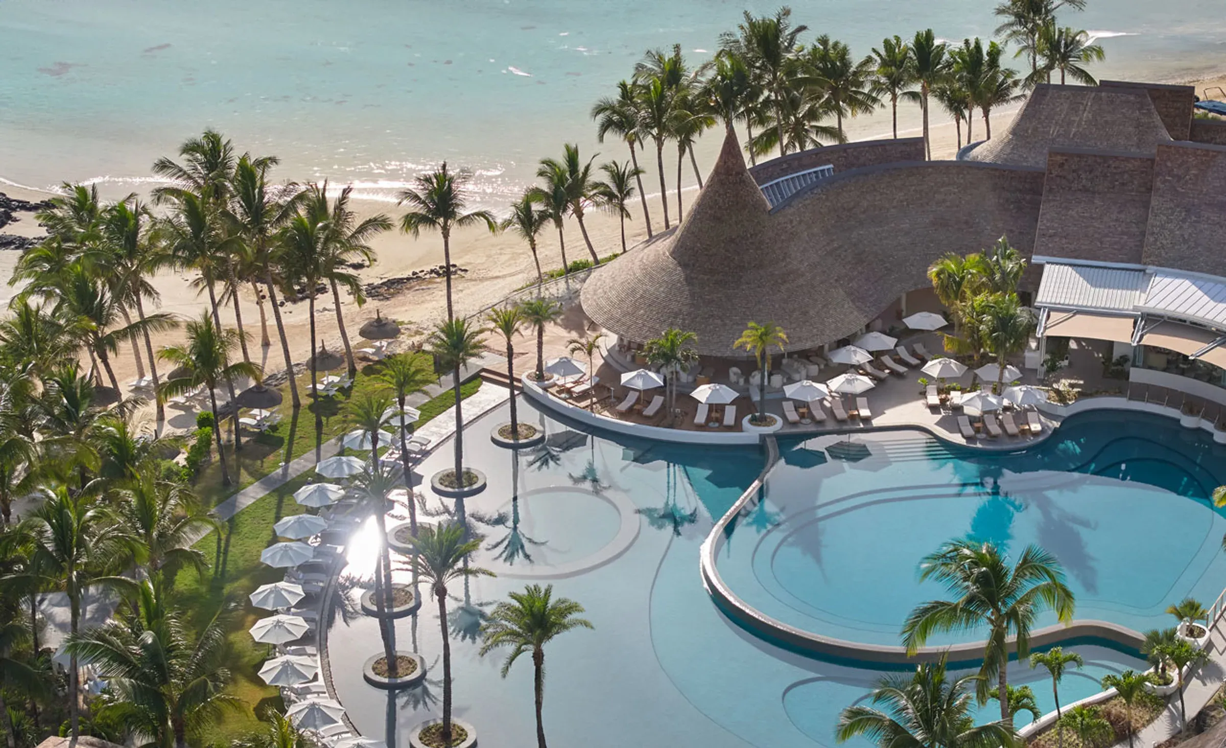 Aerial view of LUX* Belle Mare's beach, pool and thatched pavilions on Mauritius' east coast