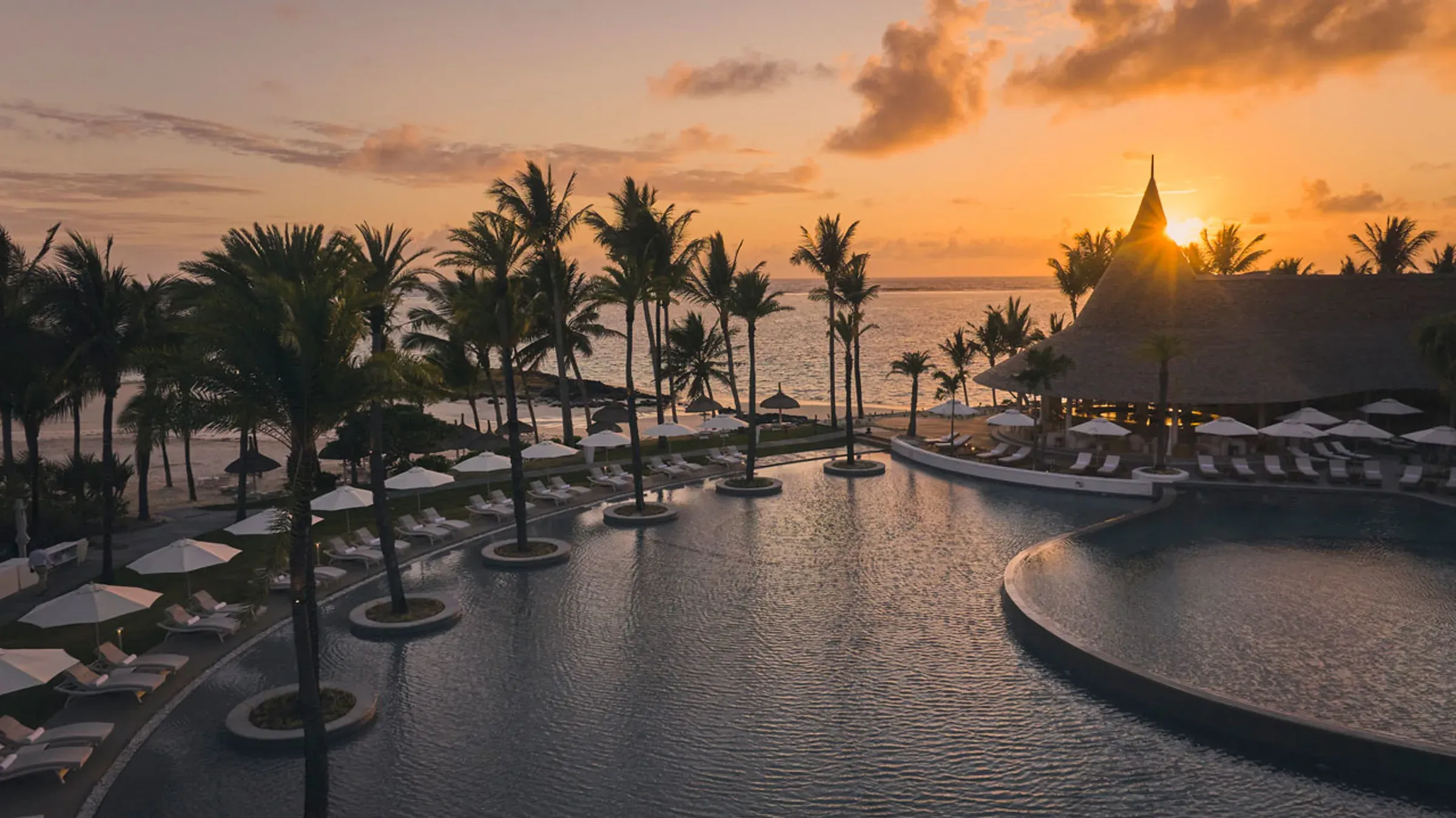 Pool at sunrise with palm trees at LUX* Belle Mare