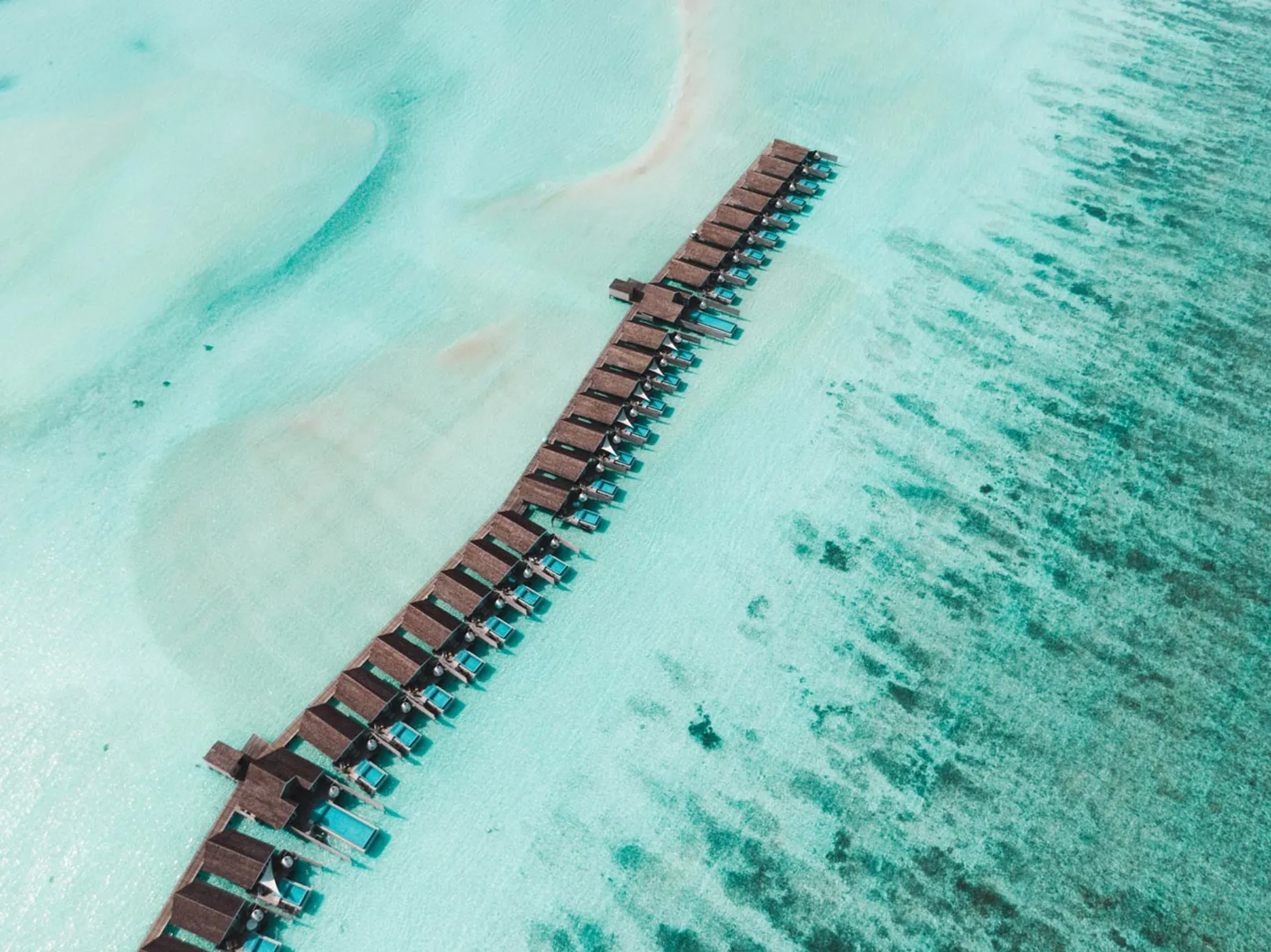 Aerial view of LUX* South Ari Atoll's overwater villas and lagoon, Maldives
