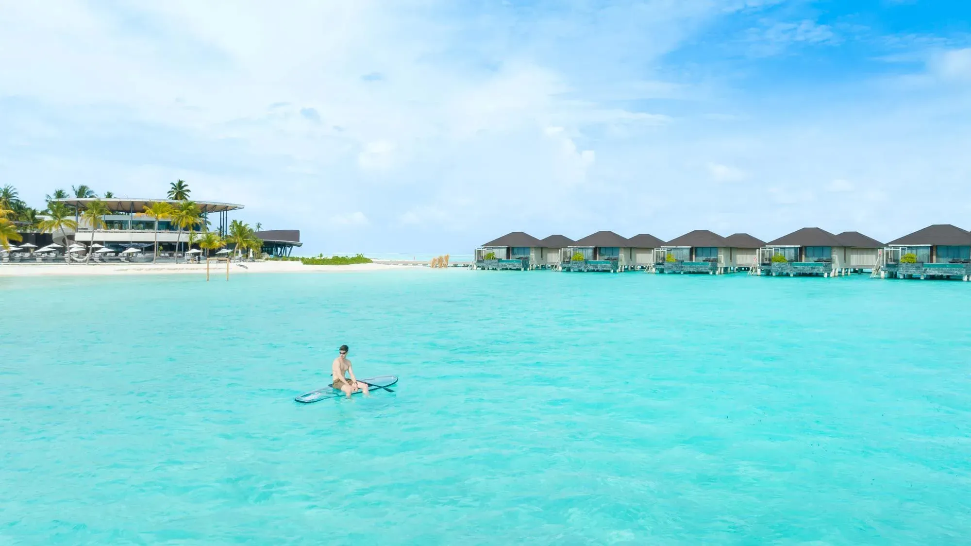 Guest paddleboarding in the lagoon near the overwater villas