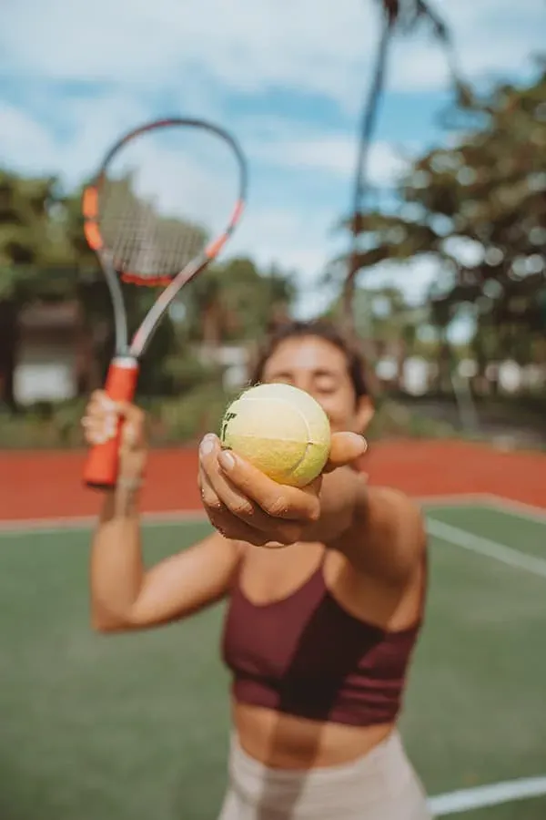 Tennis player holding a racket and ball on the floodlit court at Maradiva