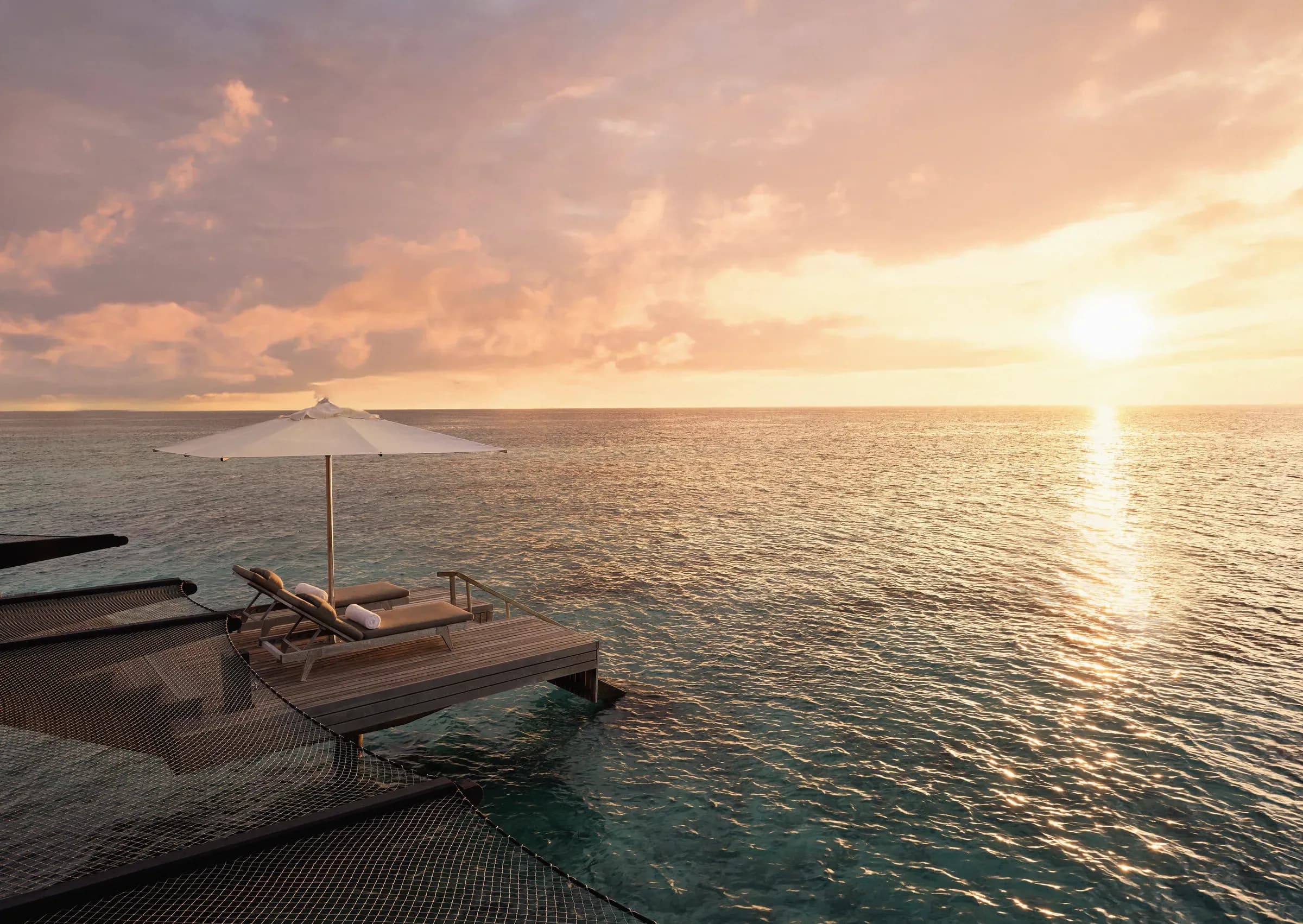 Sunset view from an overwater deck with sun loungers at One&Only Reethi Rah, Maldives