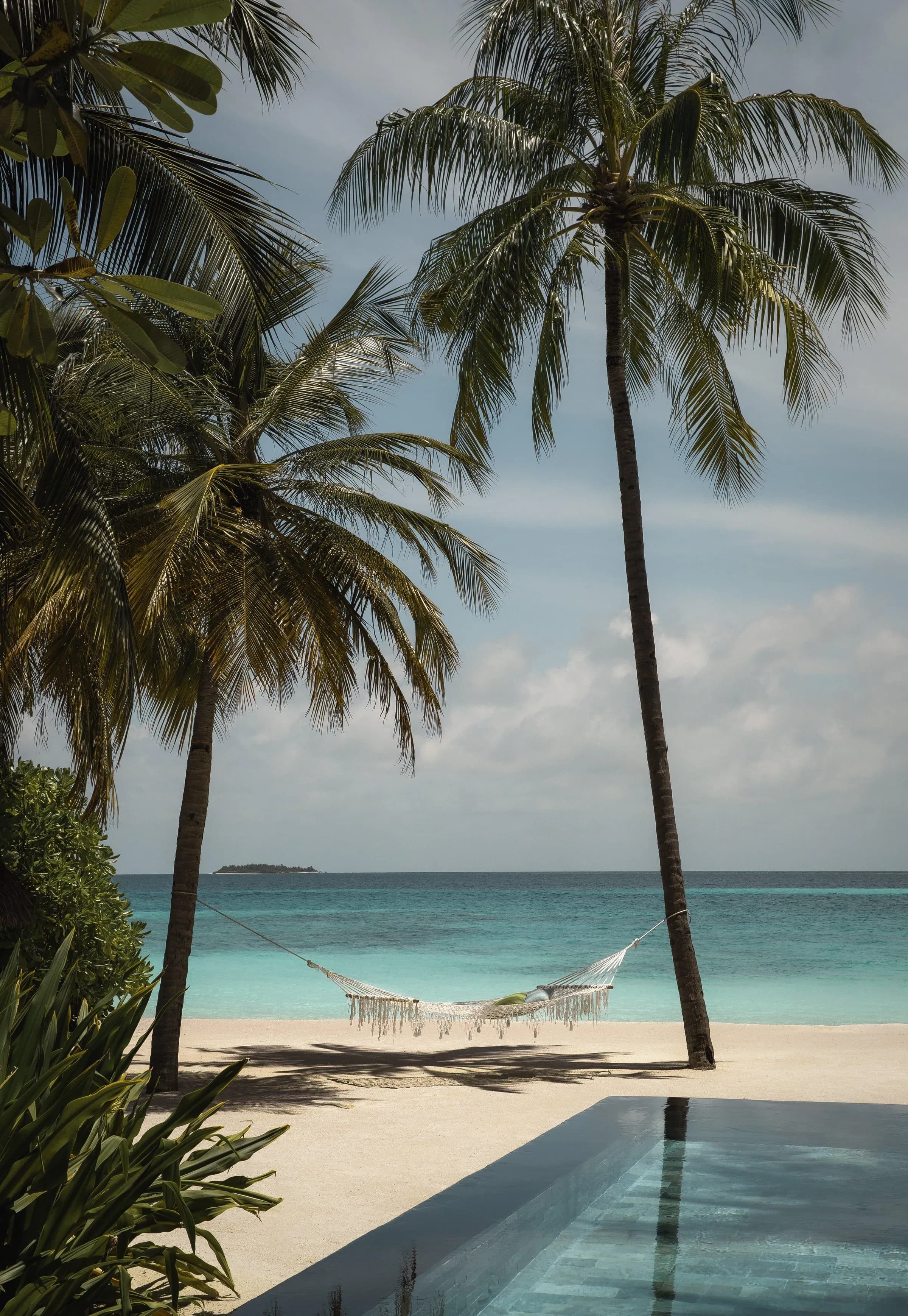 Palm-fringed beach and turquoise lagoon with a hammock at One&Only Reethi Rah
