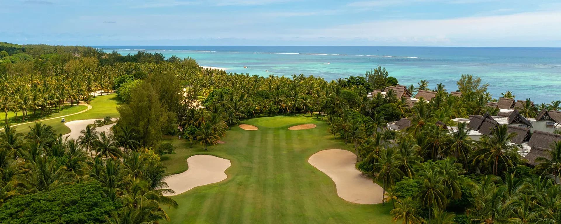 Aerial view of the golf course fairway and bunkers at Paradis Beachcomber, with the ocean beyond