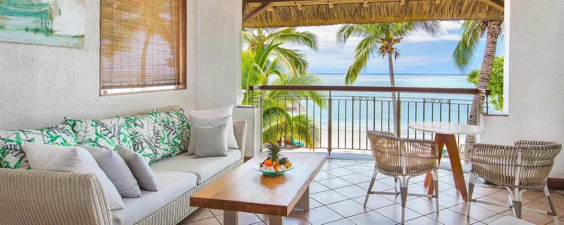 Beachfront terrace lounge with palm trees and lagoon view at Paradis Beachcomber Golf Resort & Spa