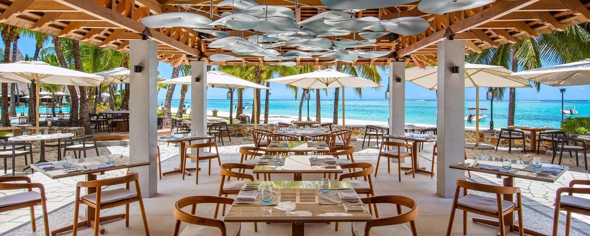 Oceanfront terrace dining at Blue Marlin restaurant, Paradis Beachcomber, beneath a canopy of fish-shaped pendant lights