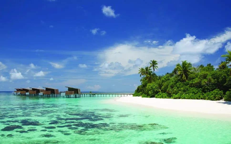 Overwater villas and turquoise lagoon fringed by white sand at Park Hyatt Maldives Hadahaa