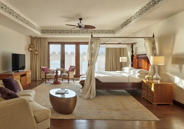 Suite bedroom at Park Hyatt Zanzibar with four-poster bed and Omani-style arched windows