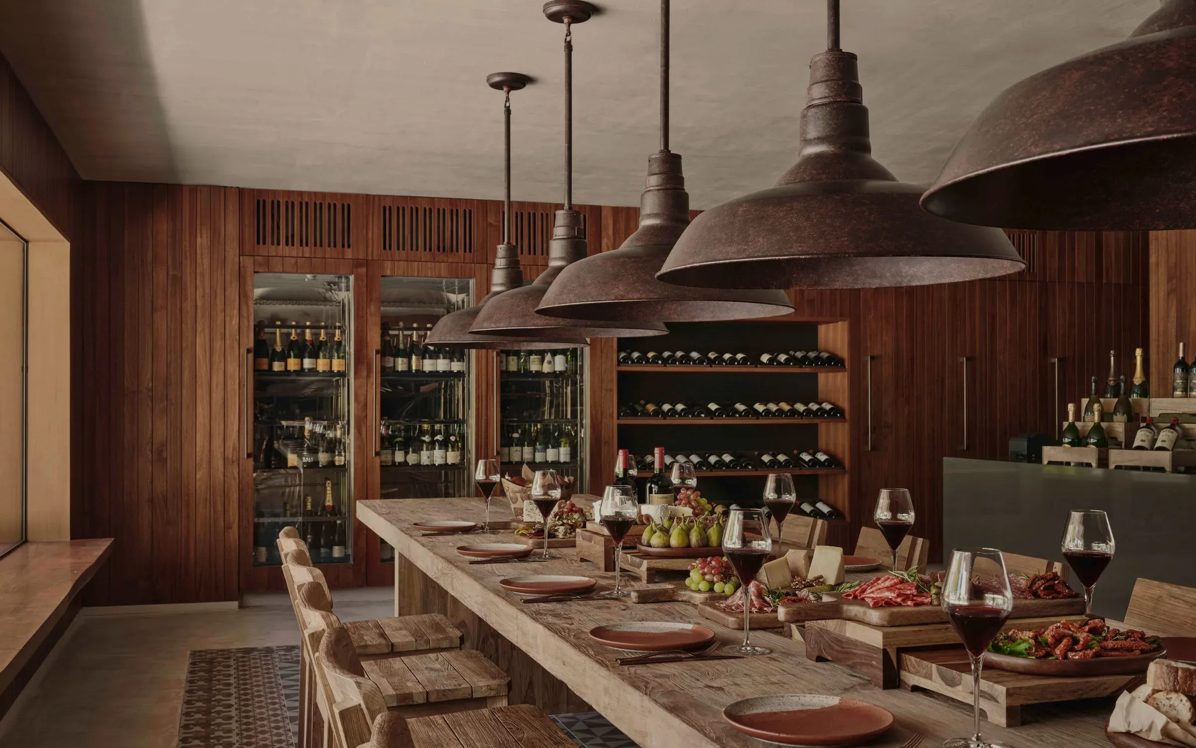 Communal dining table with wine and pendant lights at Farine, Patina Maldives