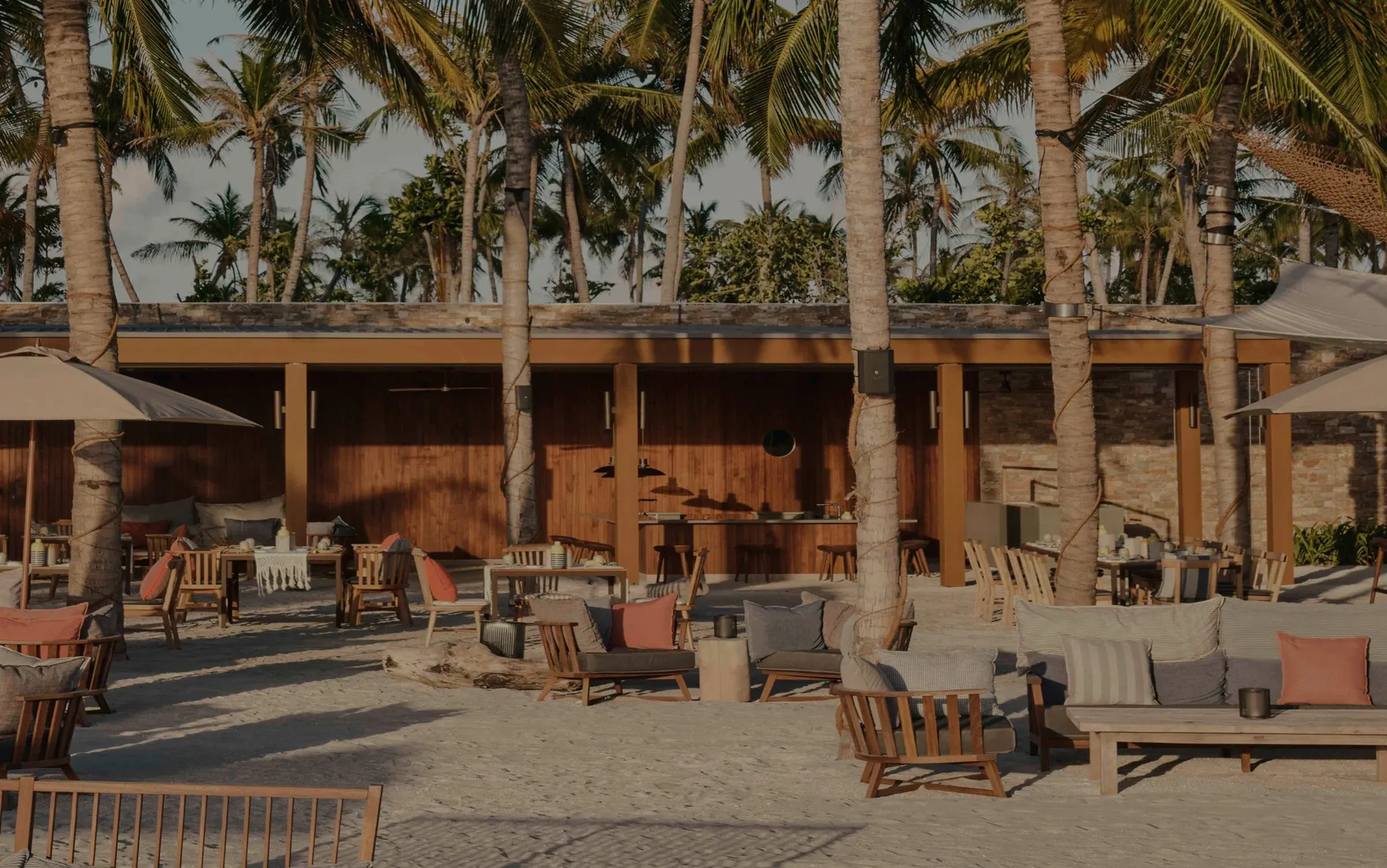 Lounge seating beneath tropical palm canopy at Helios restaurant, Patina Maldives
