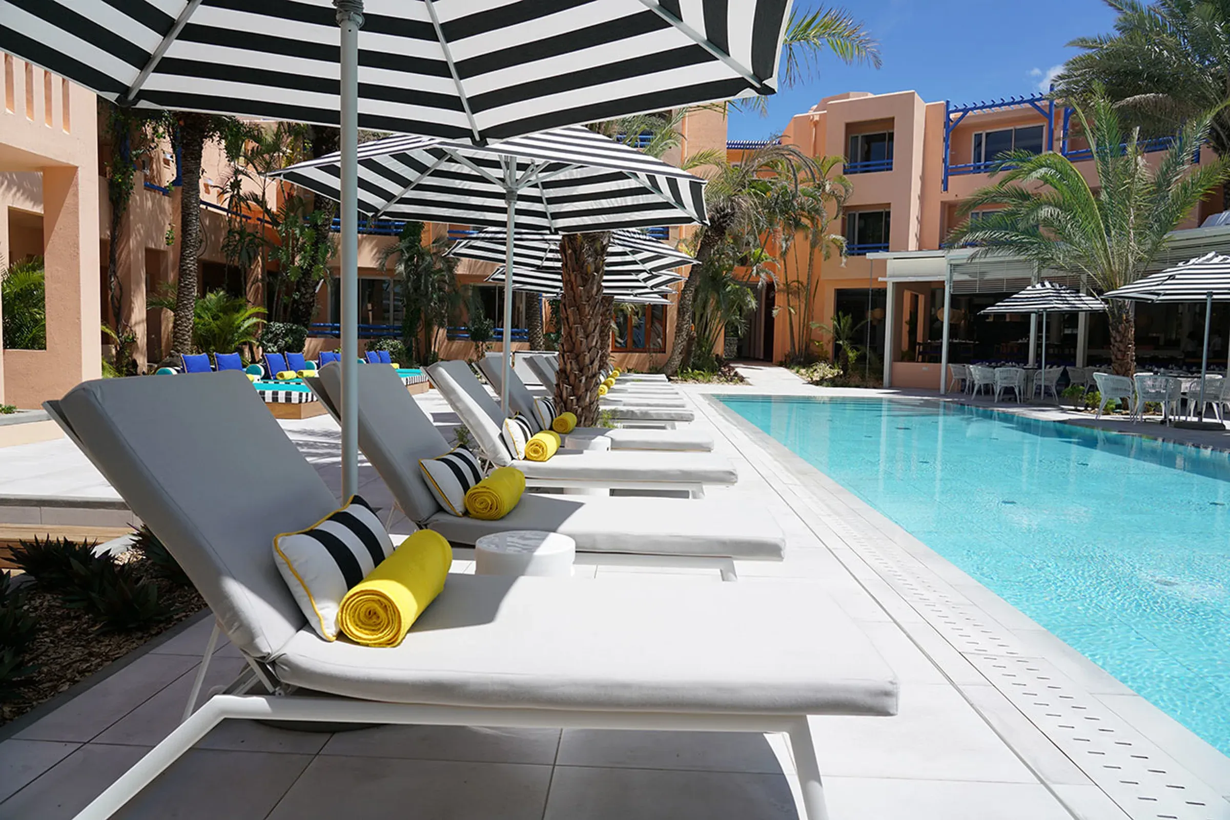 Pool deck and striped umbrellas beneath the terracotta pavilions at SALT of Palmar