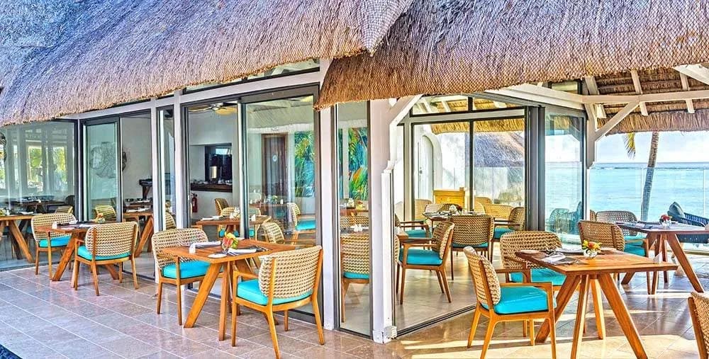 Epicure restaurant terrace under a thatched roof by the ocean at Seasense Boutique Hotel & Spa