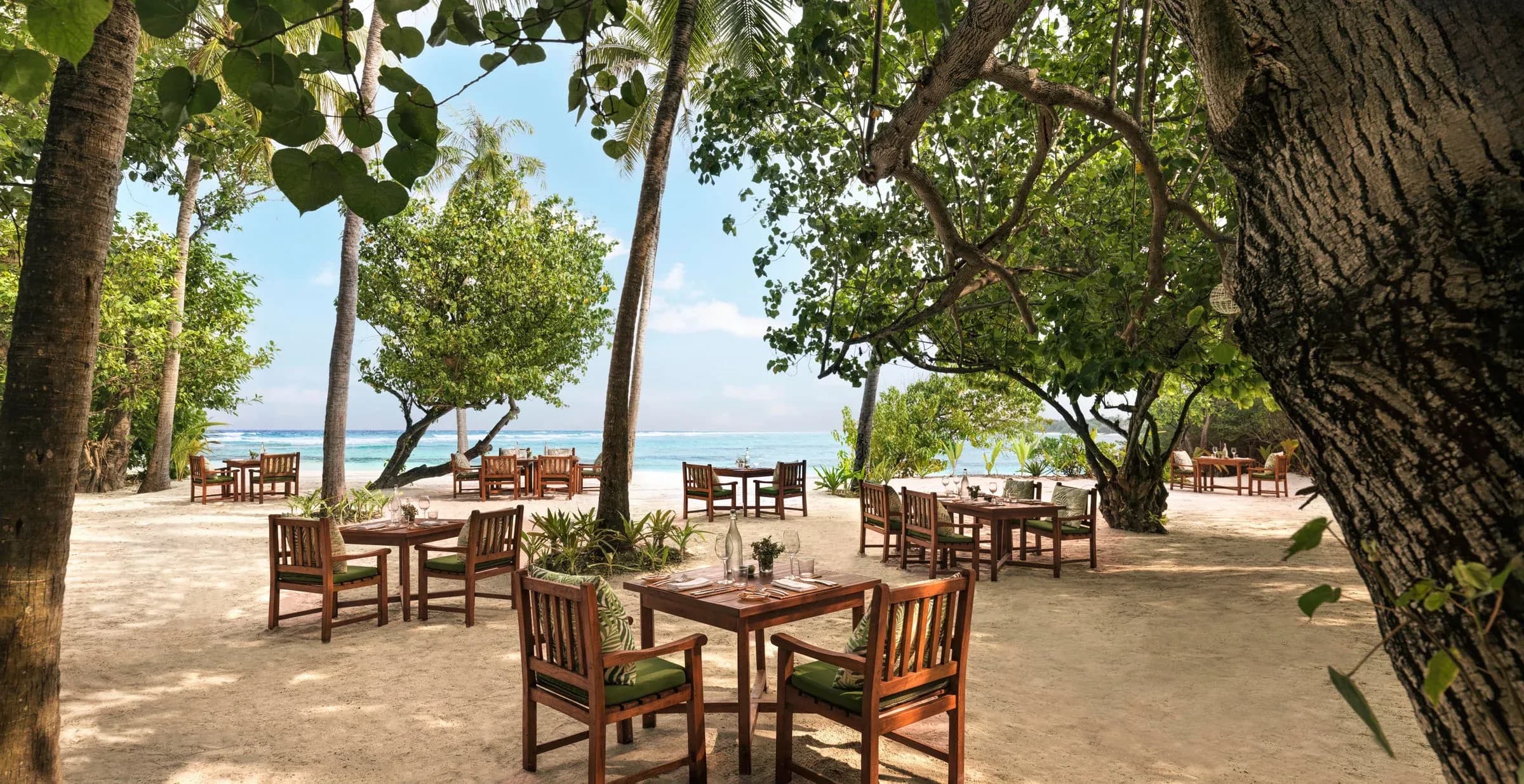Dining tables beneath the trees at Drift, Six Senses Kanuhura's restaurant on Jehunuhura island