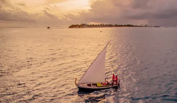 Traditional dhoni sailing at sunset off Six Senses Laamu