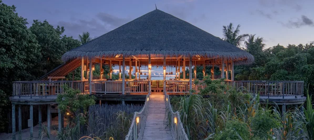 Longitude restaurant's thatched open-air pavilion at dusk, Six Senses Laamu