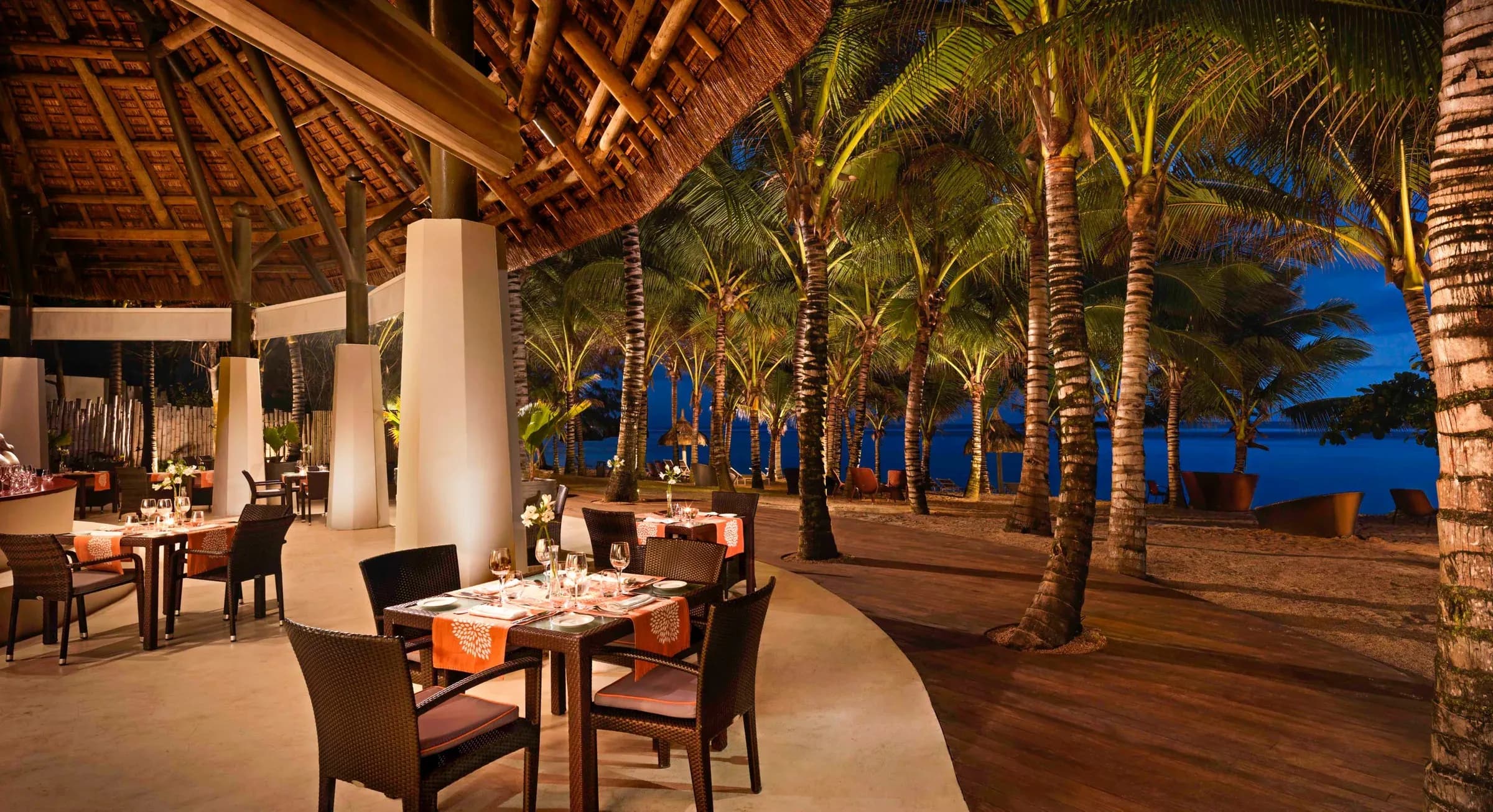 Candlelit terrace dining beneath palm trees at La Plage, SO Sofitel Mauritius