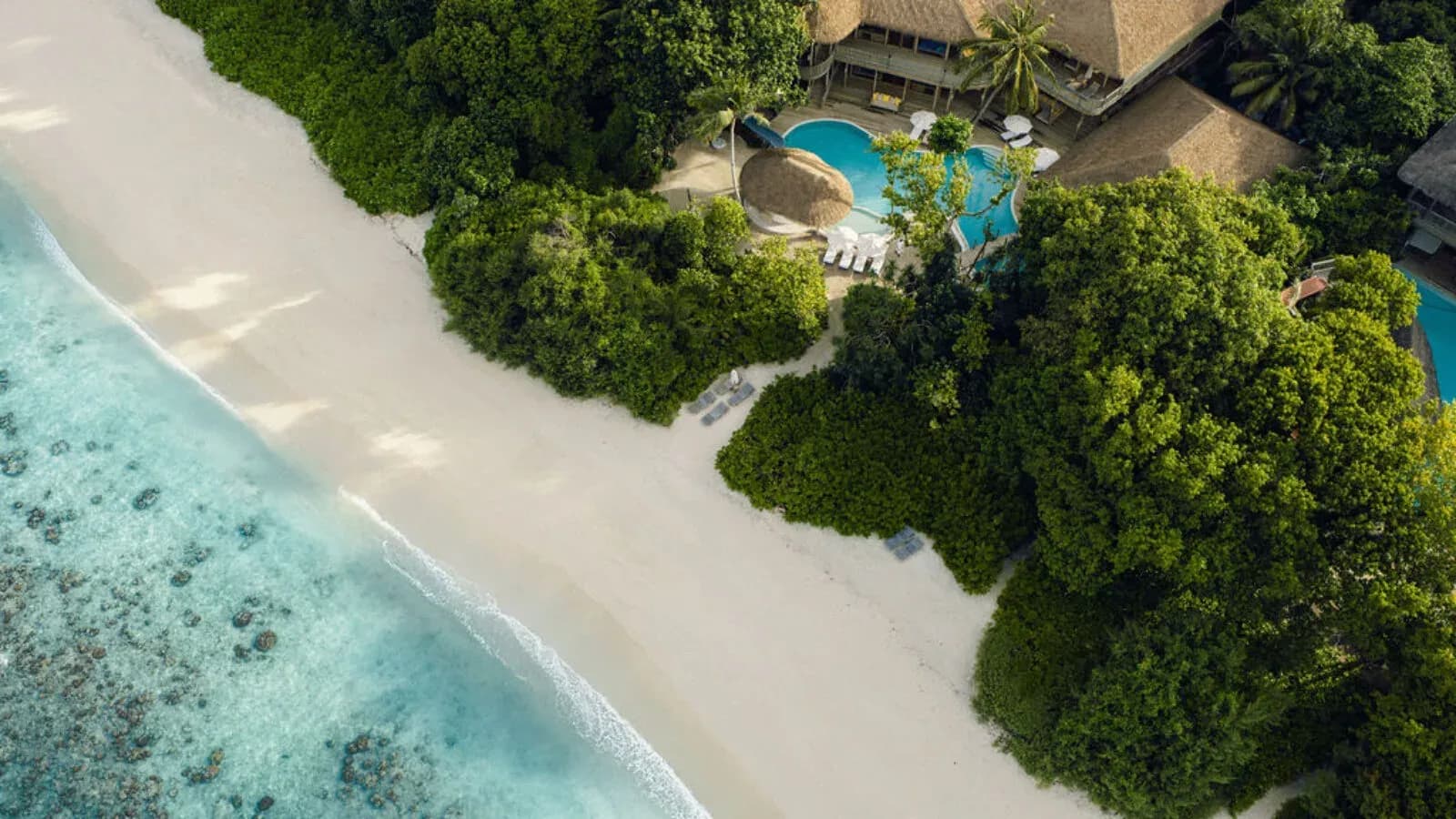 Aerial view of a beachfront villa with private pool set among dense jungle greenery at Soneva Fushi