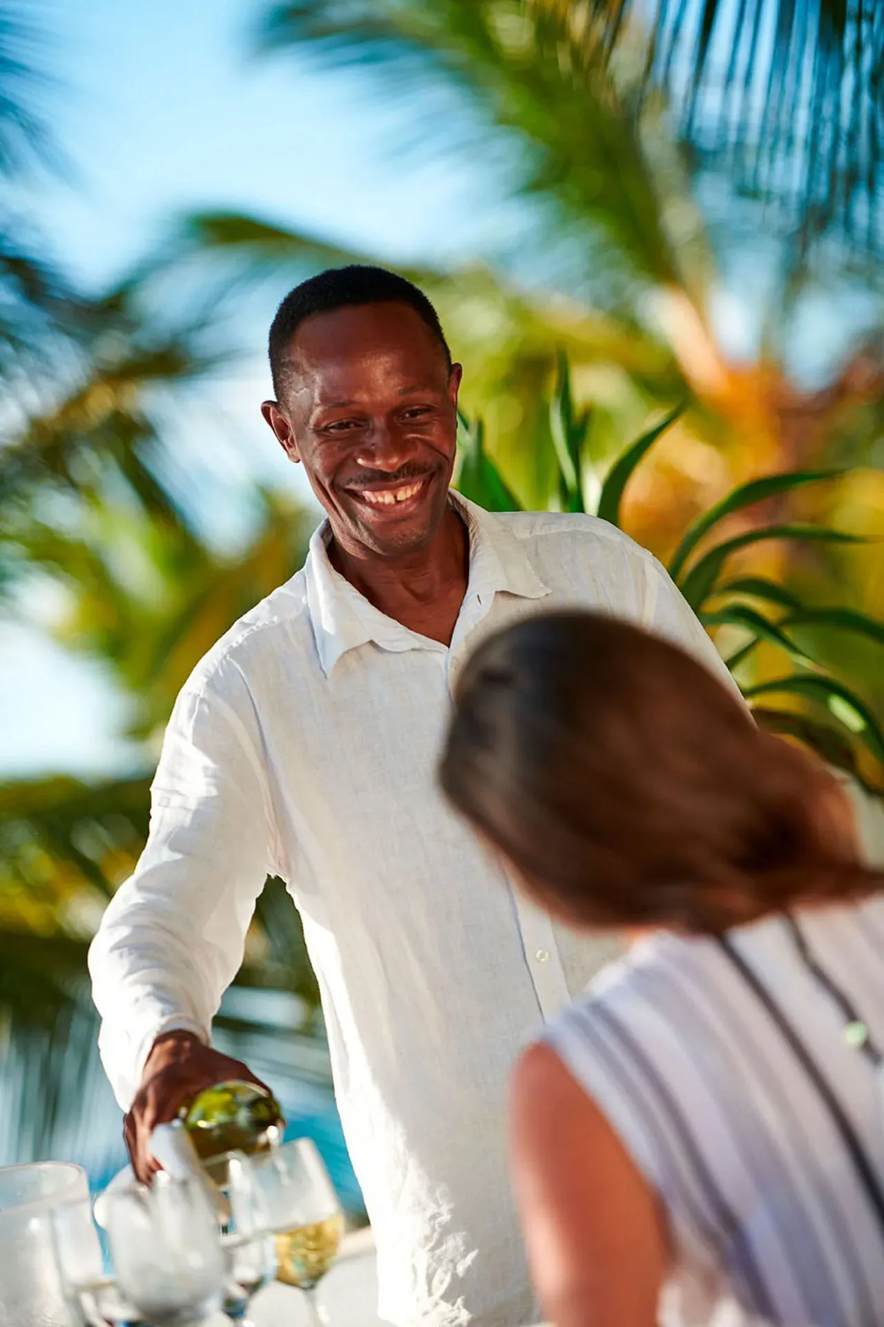 Waiter serving guests at Neema Restaurant's beachside terrace, The Aiyana, Pemba Island