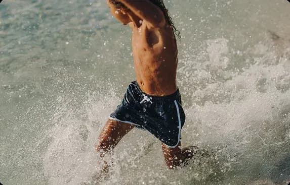 Guest wading through the surf at The Mora Zanzibar's beach