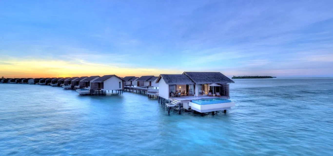 Row of overwater villas at sunset with pink and blue sky, The Residence Maldives at Falhumaafushi