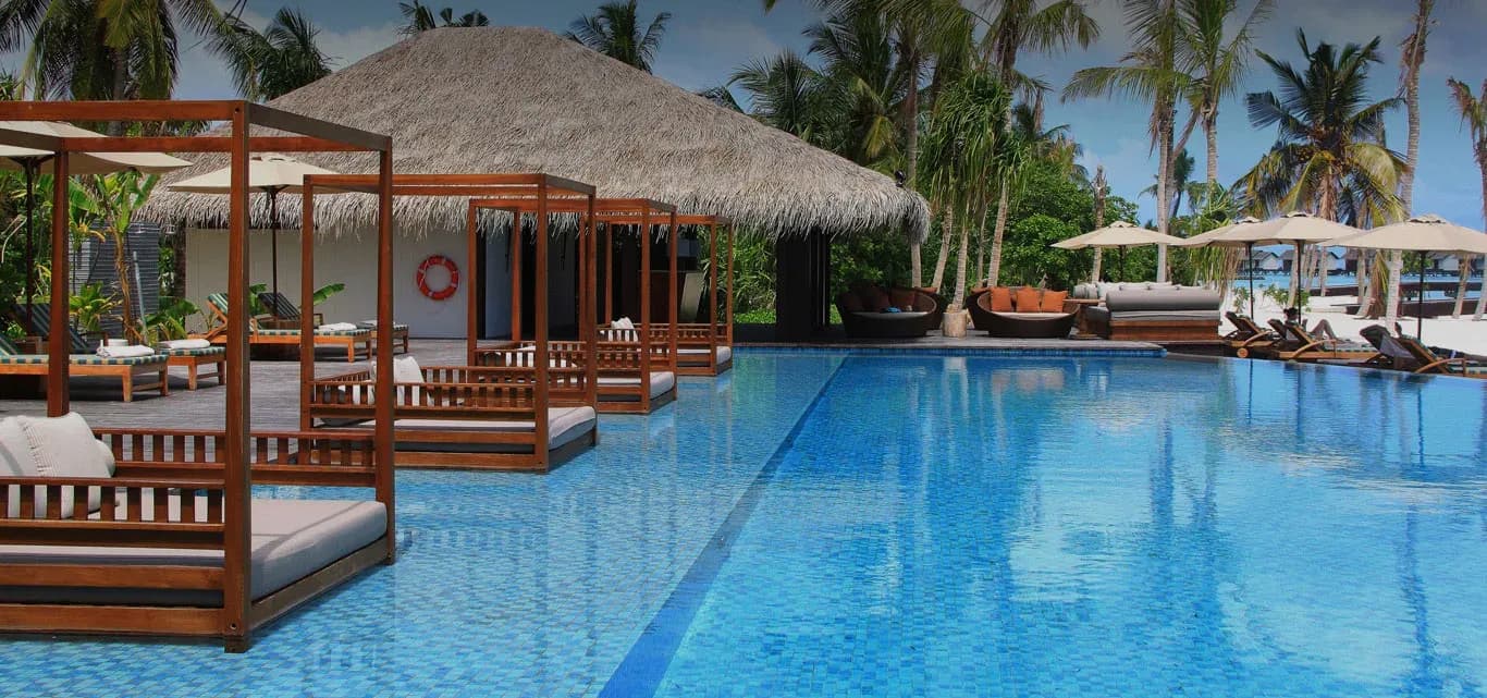 The Beach Bar cabanas beside the pool with overwater villas beyond, The Residence Maldives at Falhumaafushi
