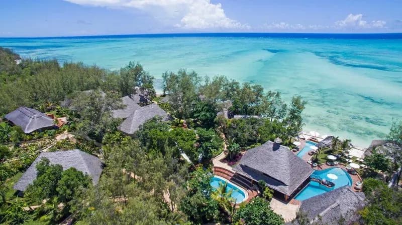 Aerial view of Tulia Zanzibar's beachfront pool and thatched pavilions on the clifftop above the Indian Ocean