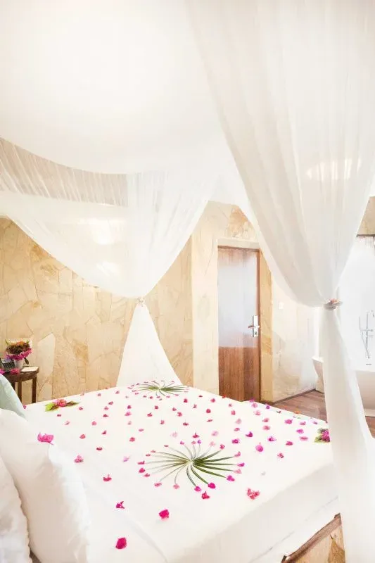 Canopy bed and open-plan bathroom in a Seafront Luxury Villa at Tulia Zanzibar