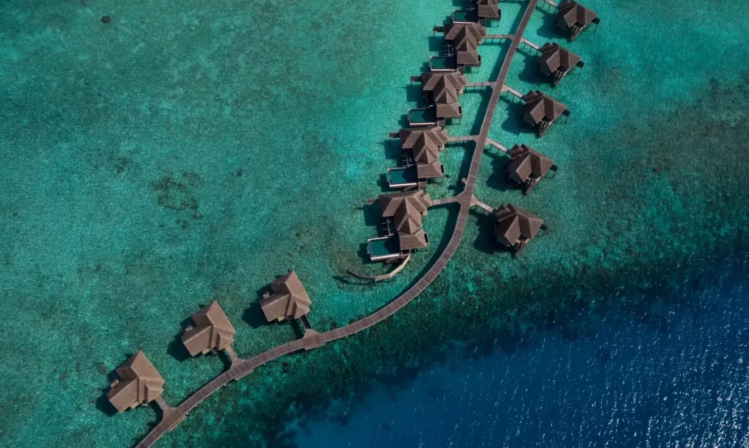 Aerial view of overwater villas on stilts above the reef at Vakkaru Maldives, Baa Atoll